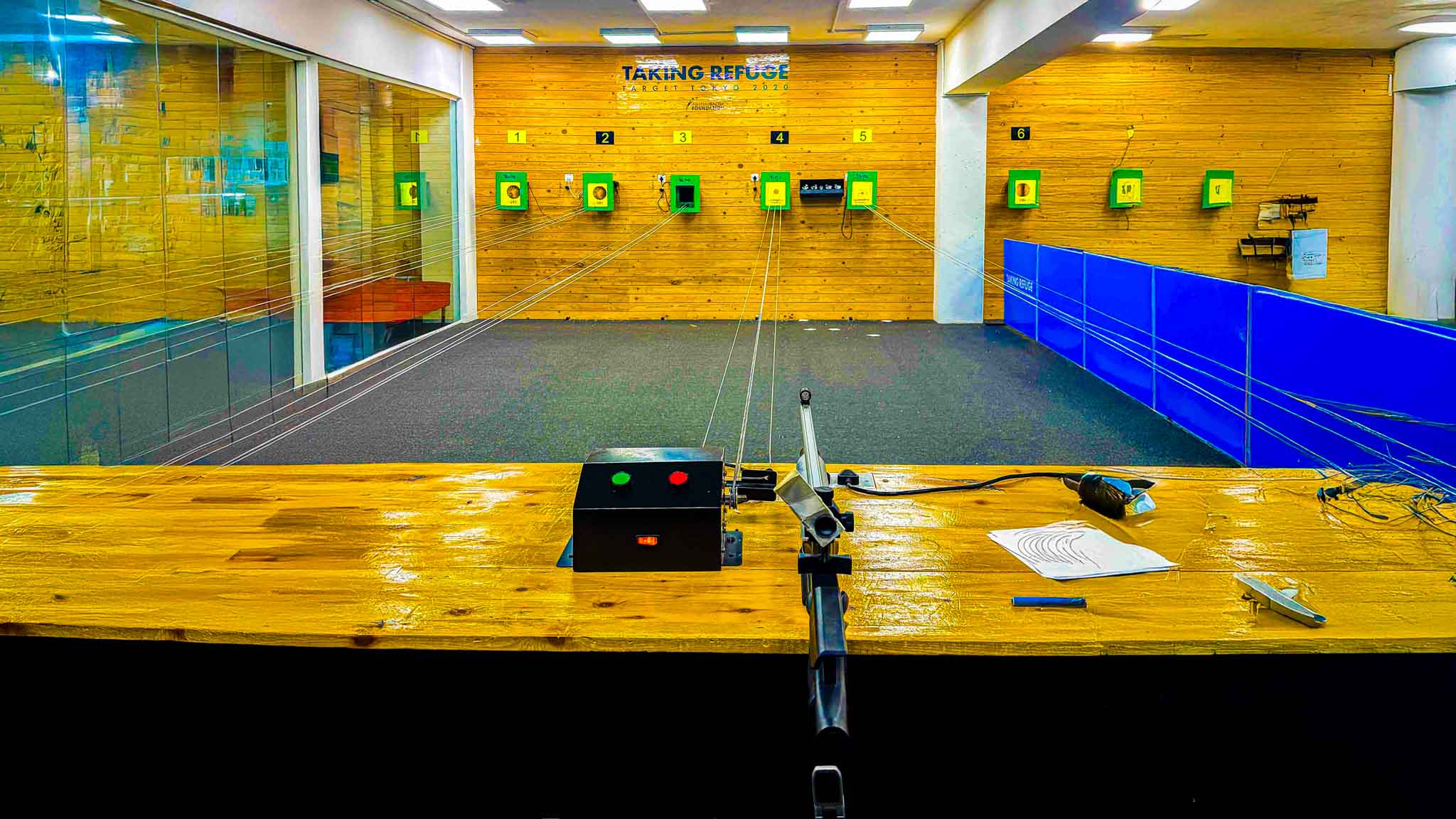 View of multiple shooting targets lined up on a wooden wall in a professional indoor shooting range.